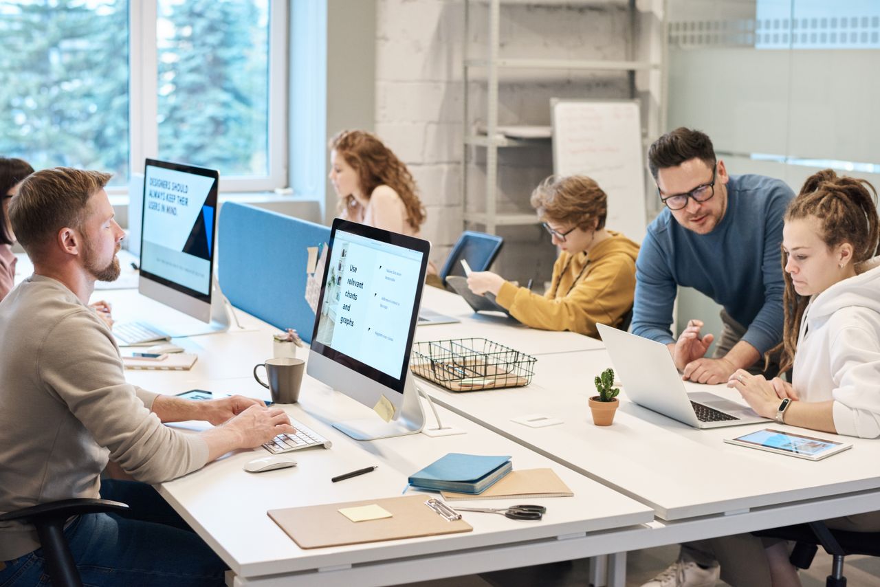 home-hero Team collaboration in a modern office setting with computers and diverse employees working together.